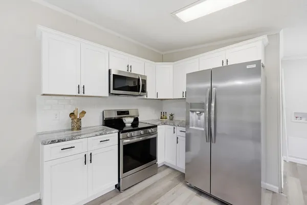 a large white kitchen with cabinets table and chairs