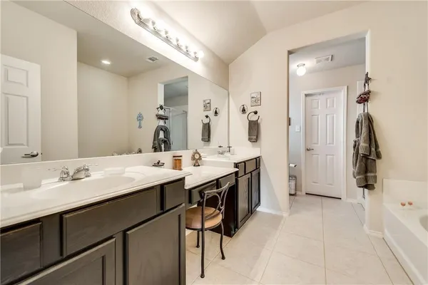 a spacious bathroom with a double vanity sink a mirror and a bathtub