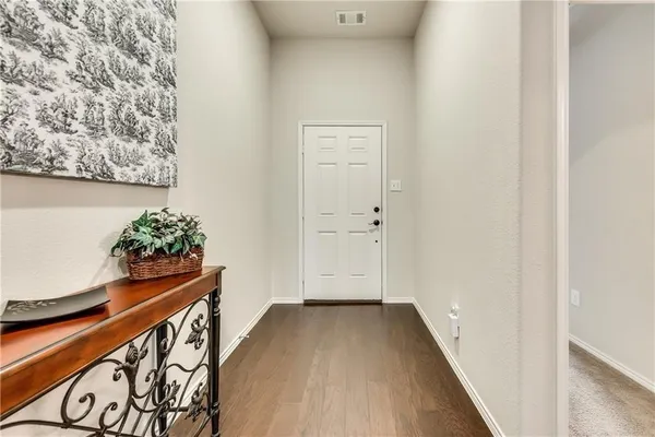 a view of a hallway with wooden floor and a potted plant