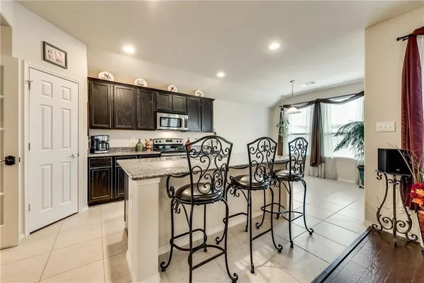 a kitchen with stainless steel appliances a dining table chairs refrigerator and sink