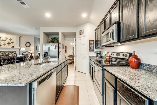 a kitchen with stainless steel appliances granite countertop a sink a stove and a refrigerator