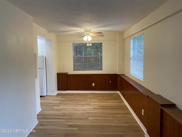 a view of empty room with wooden floor and fan