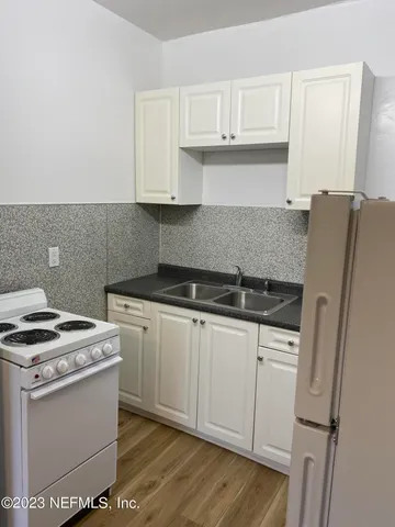 a kitchen with granite countertop white cabinets and white appliances