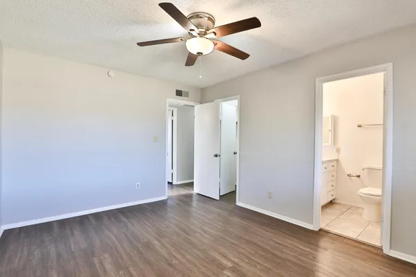 a view of an empty room and wooden floor and a ceiling fan