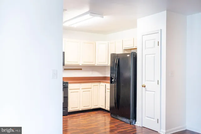 a view of a refrigerator in kitchen and an empty room