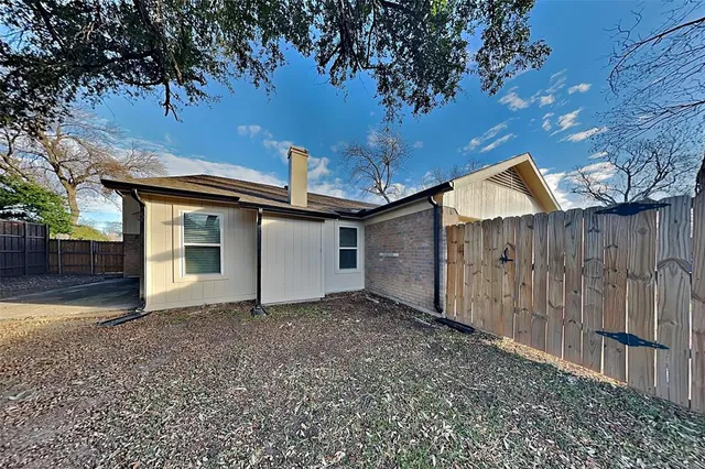 a view of a house with a large tree and wooden fence