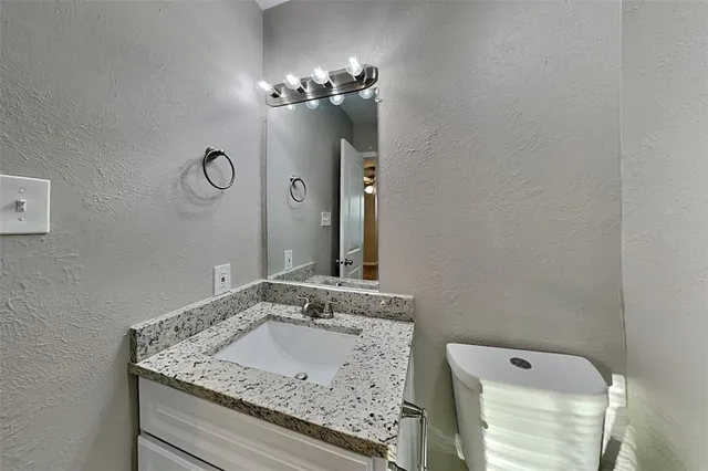 a bathroom with a granite countertop sink a light fixture and a mirror