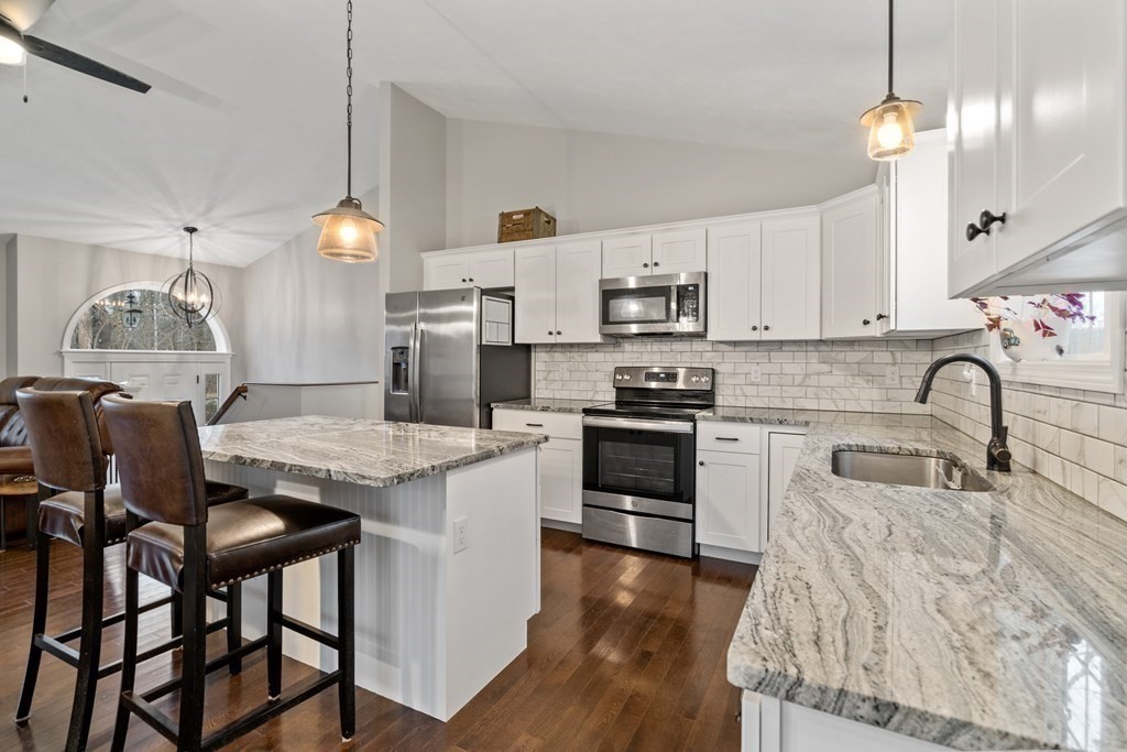 143 North Brookfield Road Barre, MA 01005 - Photo 15 of 31 a kitchen with granite countertop a stove a sink a kitchen island with a dining table and chairs