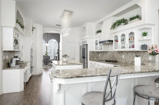 a kitchen with stainless steel appliances granite countertop a kitchen island a stove a table and chairs in it