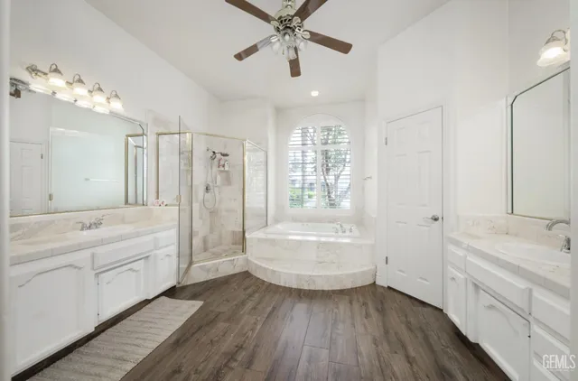 a bathroom with a tub sink vanity granite and shower