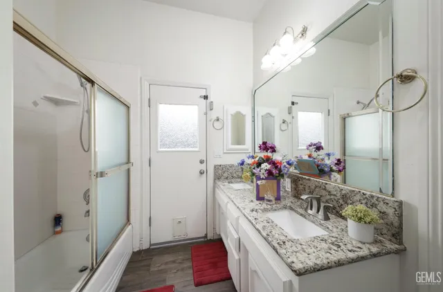 a bathroom with a granite countertop double vanity sink mirror and shower