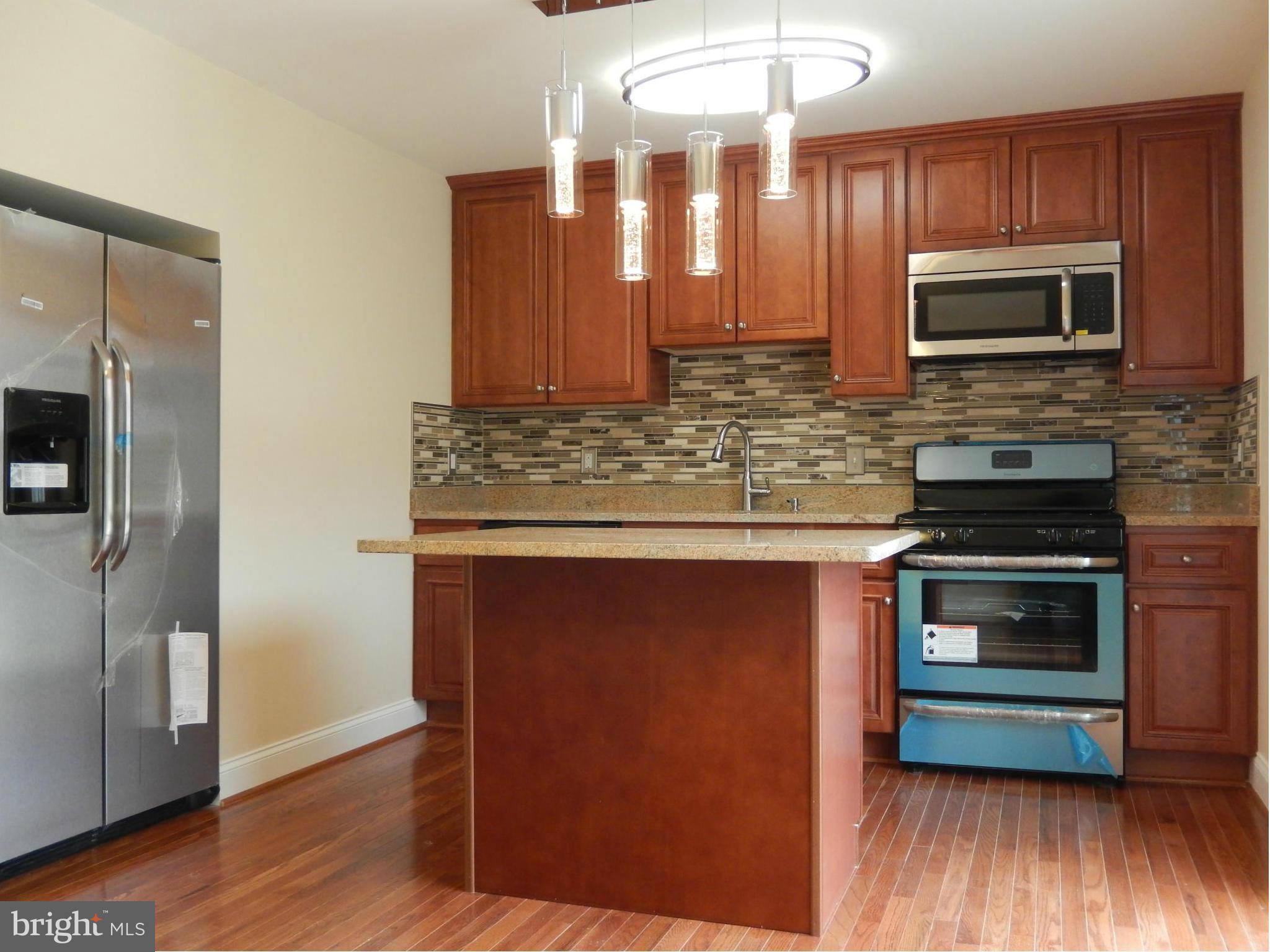 622 Charraway Road Baltimore, MD 21229 - Photo 10 of 28 a kitchen with stainless steel appliances granite countertop a stove a microwave and a refrigerator