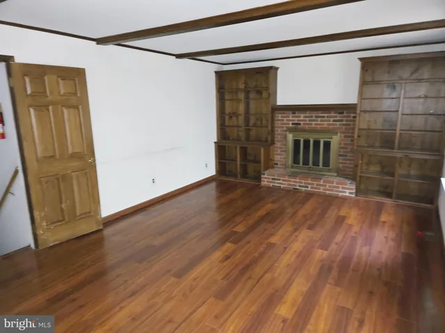 a view of a livingroom with wooden floor and a fireplace