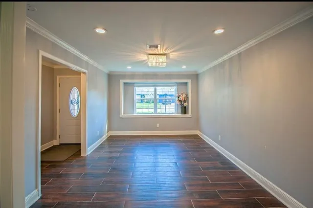 an empty room with wooden floor chandelier fan and windows