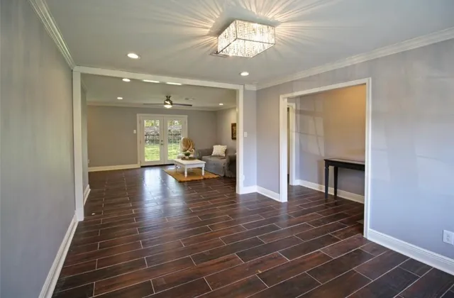 a view of a livingroom with wooden floor a ceiling fan and kitchen space