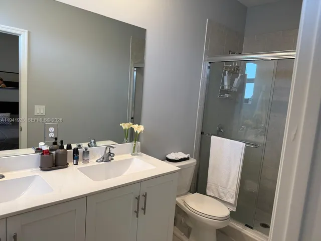 a bathroom with a sink a toilet a mirror and shower