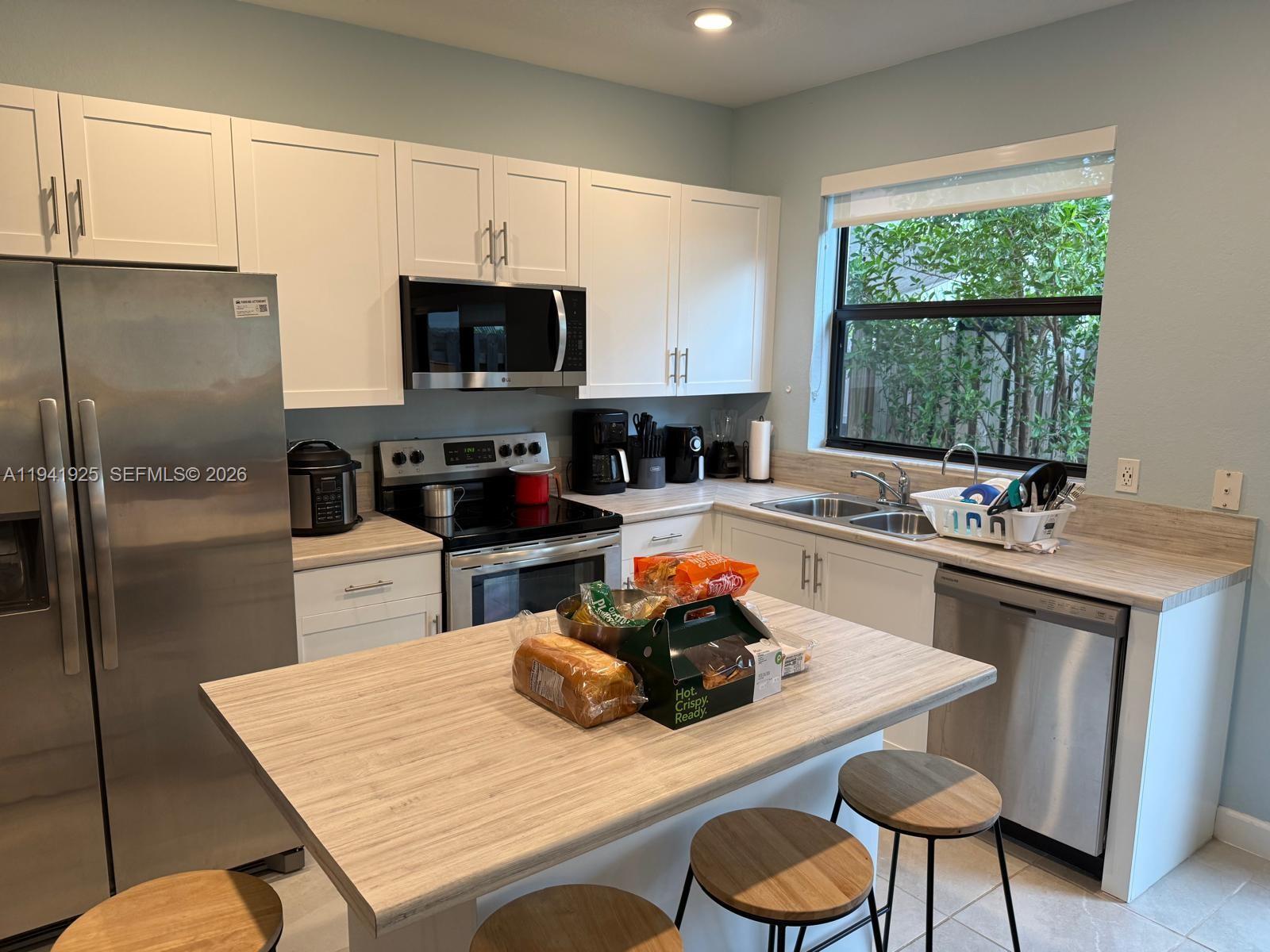 887 Northeast 211th Street Miami, FL 33179 - Photo 8 of 25 a kitchen with sink a window and chairs