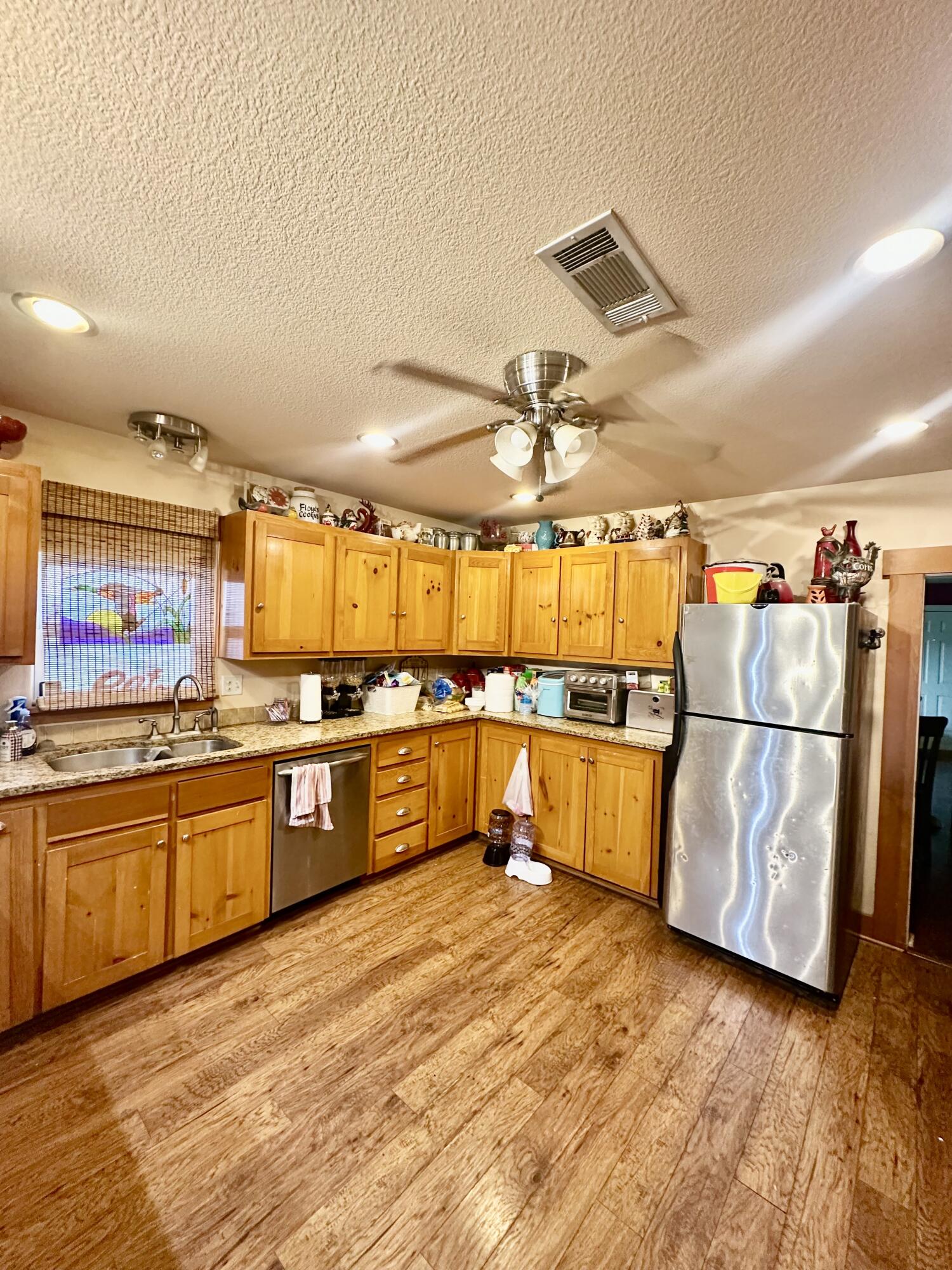 735 South 12th Street Slaton, TX 79364 - Photo 5 of 16 a large kitchen with stainless steel appliances granite countertop a lot of counter space and wooden floors