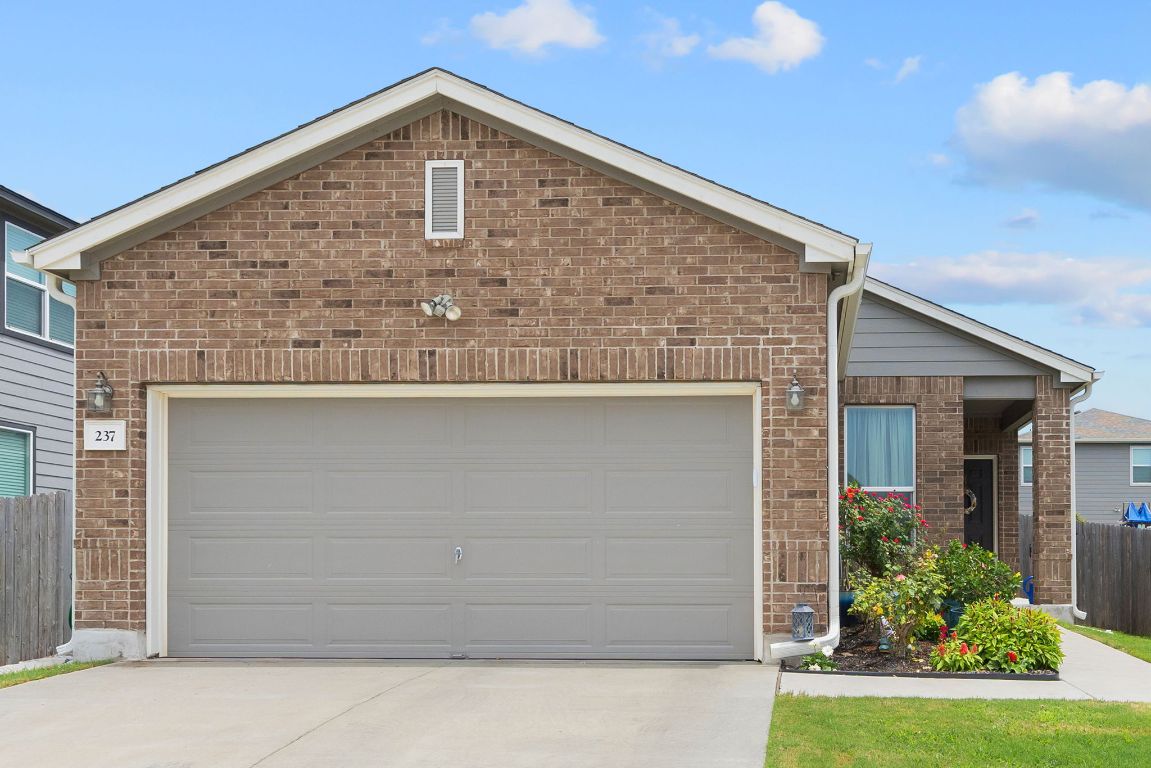 Ranch-style house with driveway, brick siding, and an attached garage