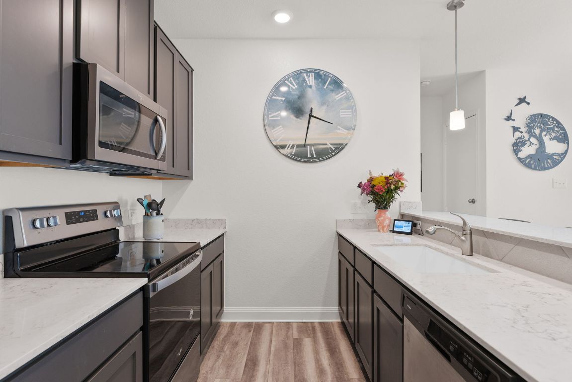 237 Benmyrtle Trail Georgetown, TX 78626 - Photo 9 of 22 Kitchen with appliances with stainless steel finishes, light wood finished floors, light stone counters, decorative light fixtures, and recessed lighting