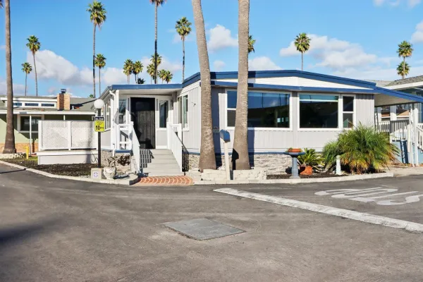a view of a house with potted plants and a car park in front of it