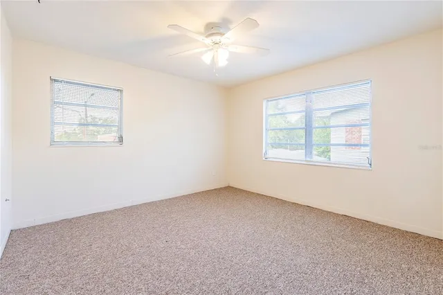 an empty room with windows and ceiling fan