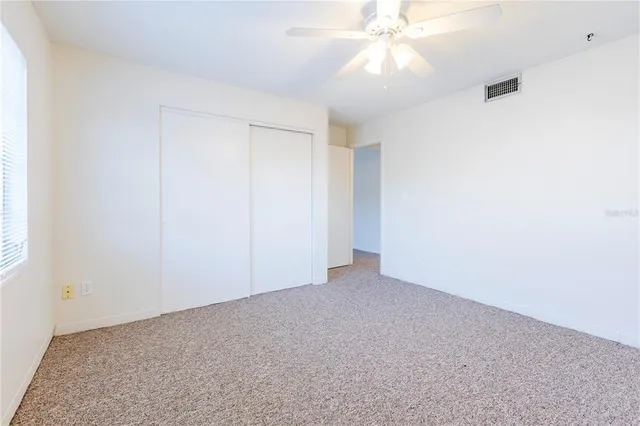 an empty room with a fan and a window