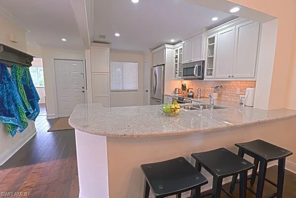 a kitchen with stainless steel appliances granite countertop a kitchen island a stove a sink a dining table and chairs