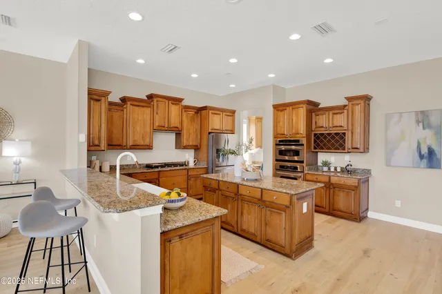 a large kitchen with stainless steel appliances a stove a sink a oven and a refrigerator