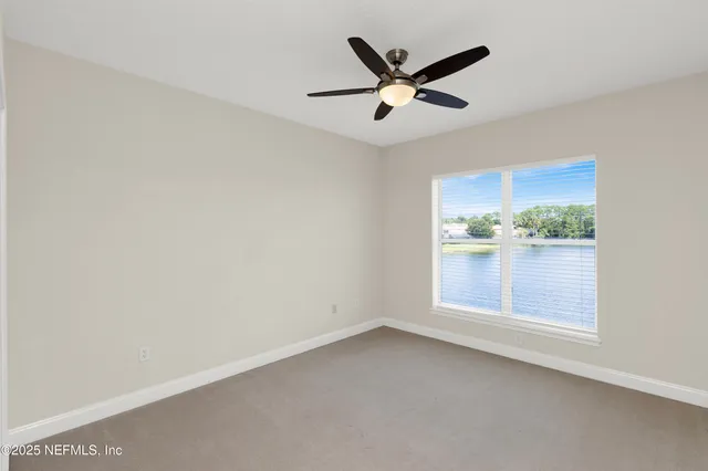 an empty room with a ceiling fan and window