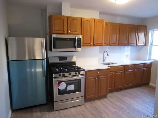 a kitchen with granite countertop wooden cabinets stainless steel appliances and a wooden floor