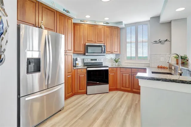 a kitchen with stainless steel appliances granite countertop wooden cabinets a stove a sink and dishwasher with wooden floor