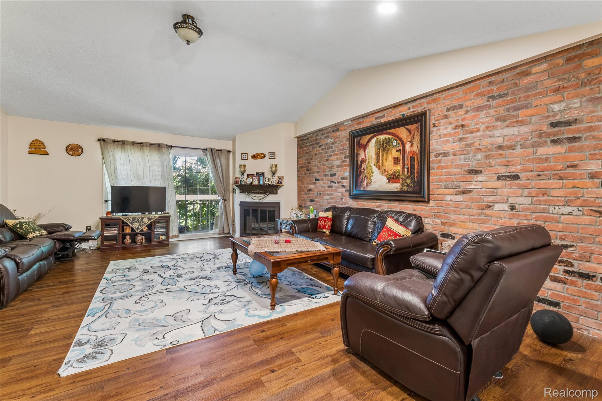 704 South Brady Road, Unit B Dearborn, MI 48124 - Photo 7 of 16 Vaulted ceilings, wood-finish flooring, exposed brick accent wall, corner fireplace with mantel, and large picture window