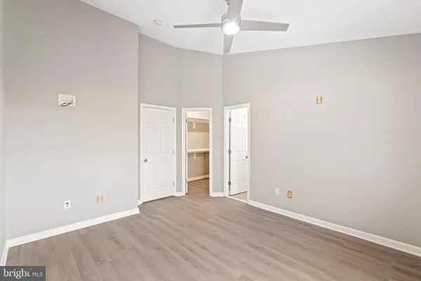 an empty room with wooden floor and ceiling fan