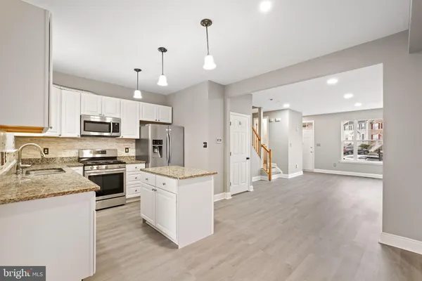 a large kitchen with white cabinets stainless steel appliances