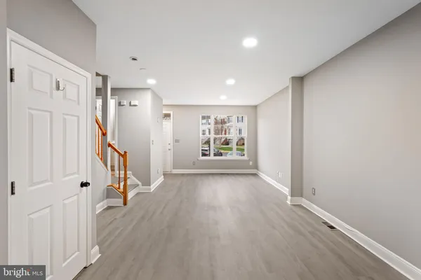 a view of an empty room with wooden floor and stairs