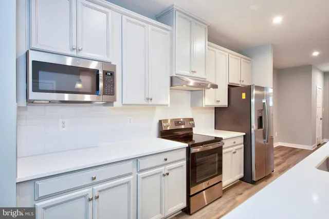 a kitchen with cabinets stainless steel appliances and a wooden floor