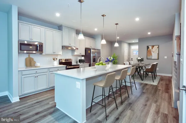 a kitchen with stainless steel appliances kitchen island granite countertop a stove a sink a refrigerator and a dining table with wooden floor