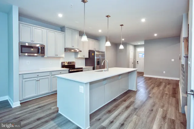 a kitchen with kitchen island a white counter top space cabinets and stainless steel appliances