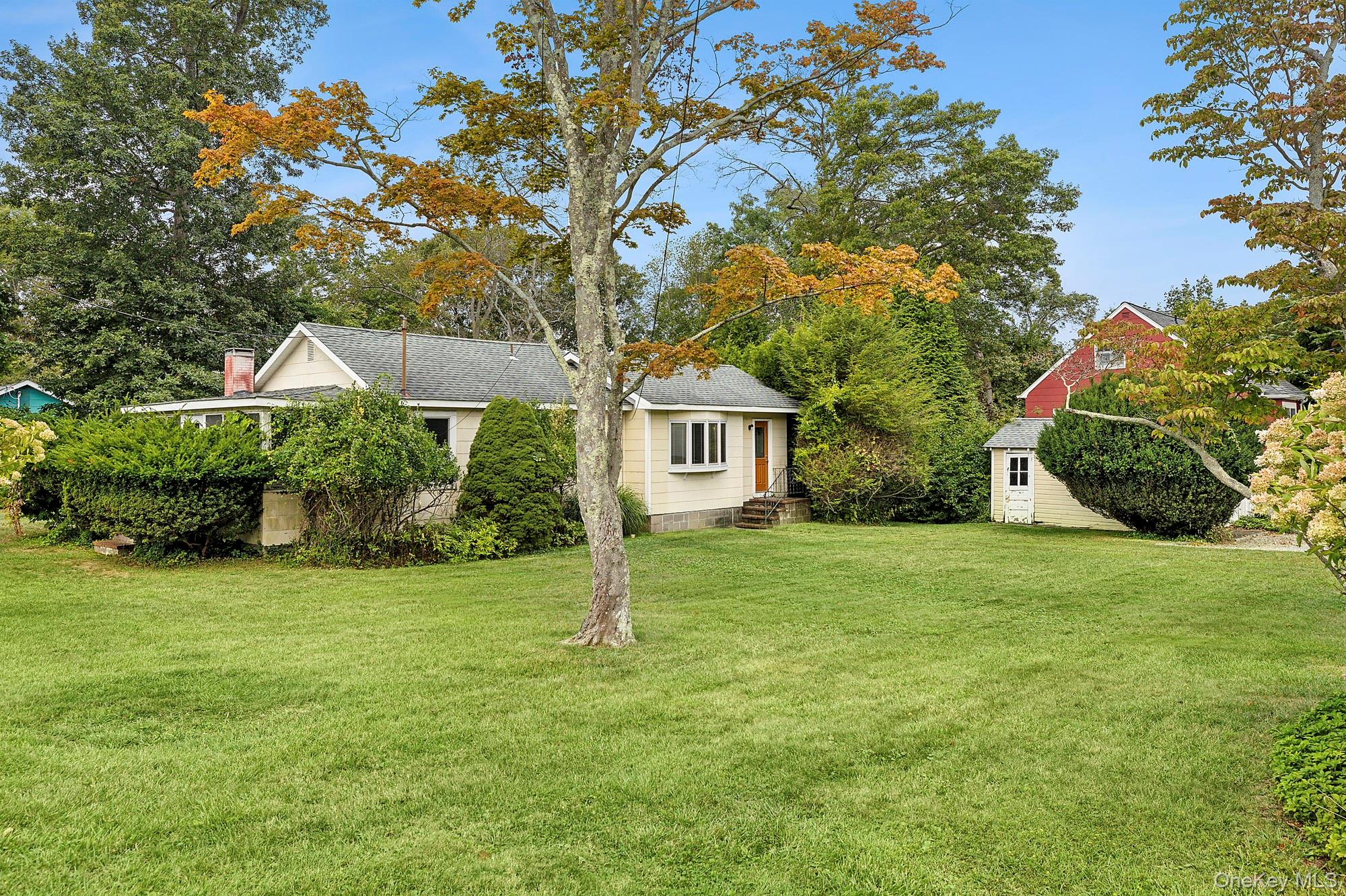 35 Saltaire Road Sound Beach, NY 11789 - Photo 1 of 1 View of front of property with a front yard, view of wooded area, a storage unit, and roof with shingles