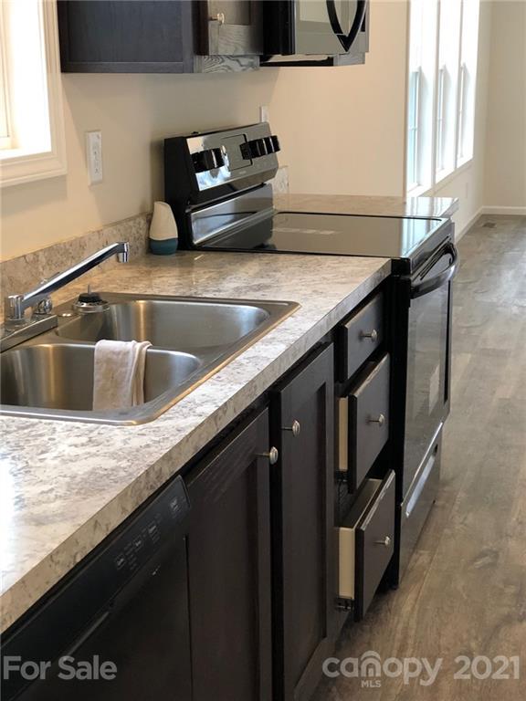 318 Souther Road Fletcher, NC 28732 - Photo 10 of 19 a kitchen with granite countertop a sink a stove and wooden cabinets