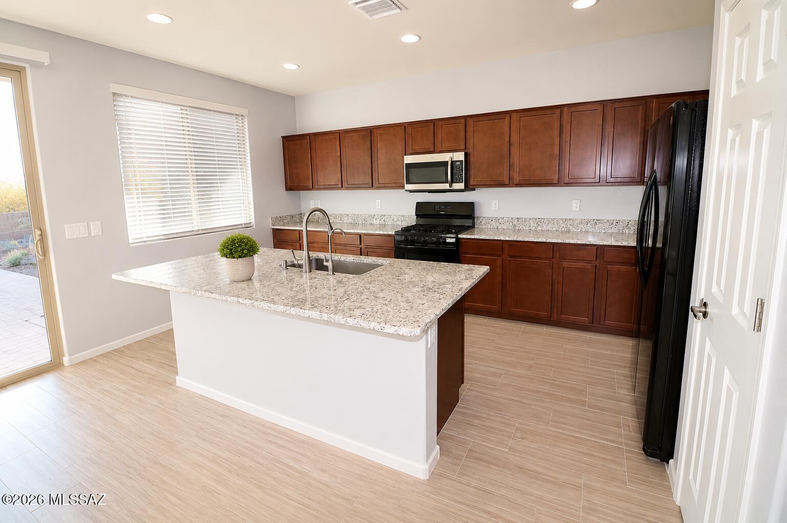 11484 East Desert Raptor Loop Tucson, AZ 85747 - Photo 3 of 28 a kitchen with granite countertop wooden cabinets a sink dishwasher a stove and refrigerator with wooden floor
