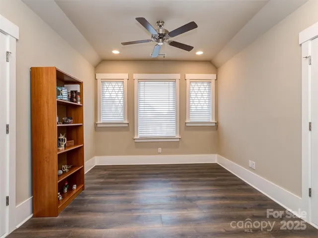 an empty room with bookshelf and windows