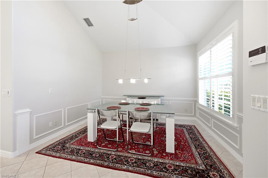 1960 Timarron Way Naples, FL 34109 - Photo 9 of 45 Vaulted ceiling dining area featuring tile flooring, wainscoting, and plantation shutters