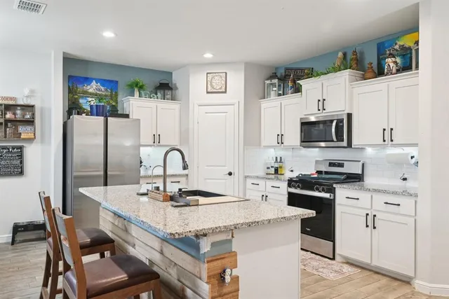 a kitchen with granite countertop a stove refrigerator and a microwave