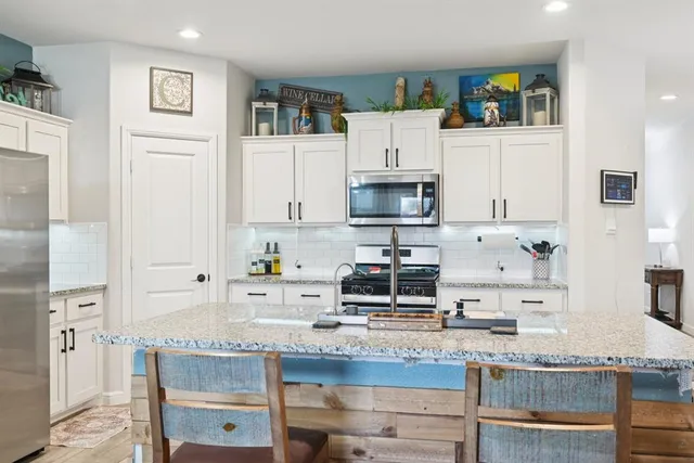 a kitchen with granite countertop white cabinets and stainless steel appliances