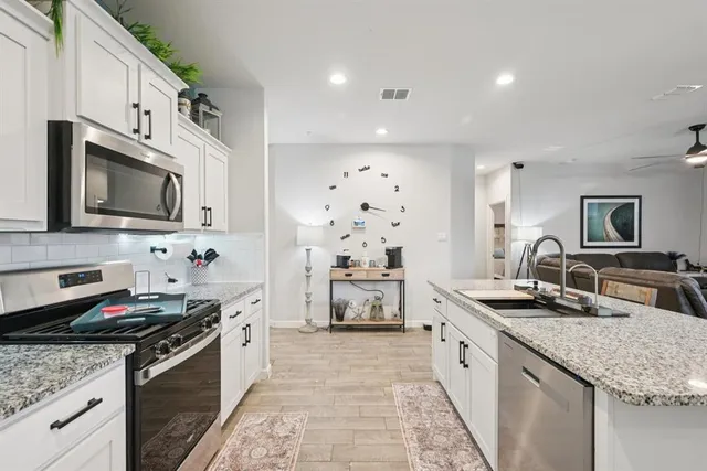a large kitchen with stainless steel appliances granite countertop a sink and a stove