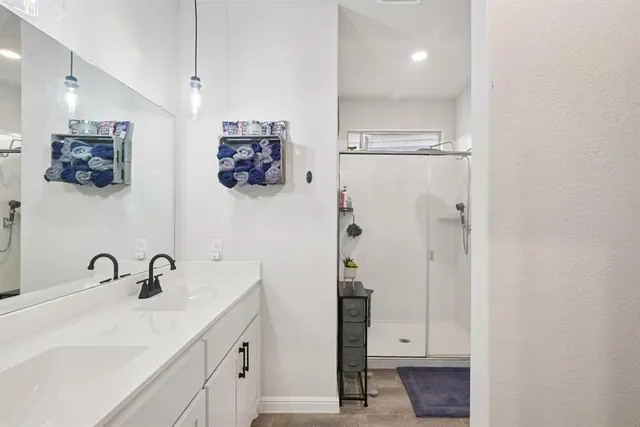 a bathroom with a sink vanity granite tub shower and mirror