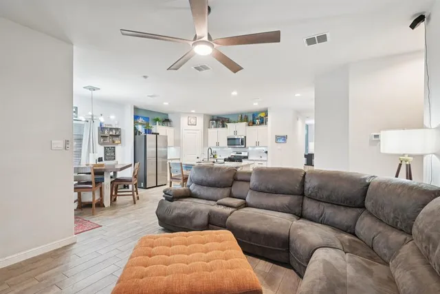 a living room with furniture kitchen view and a wooden floor