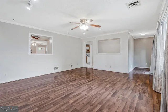 an empty room with wooden floor chandelier fan and windows